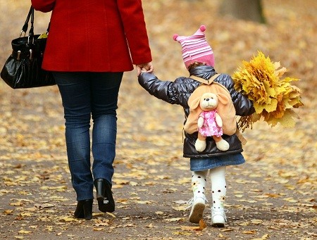 Description: Em bé cầm một bó lá vàng đi dạo trong công viên với mẹ một ngày nắng ấm ở thành phố Lviv, Ukraina